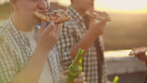 A-man-eat-piece-of-hot-pizza-and-drink-beer-on-the-party-with-his-fried.